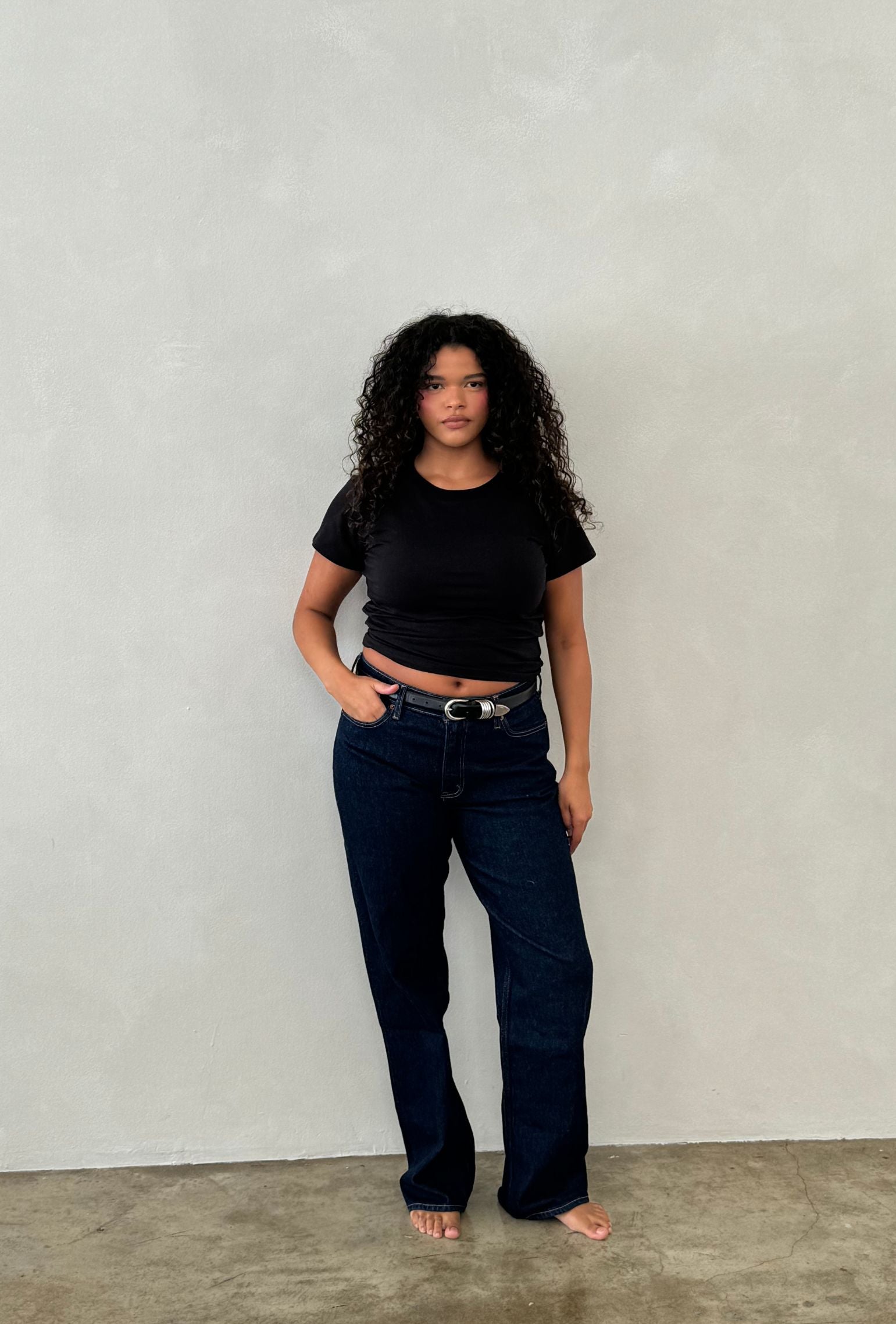 Black crew neck tee styled with dark denim jeans