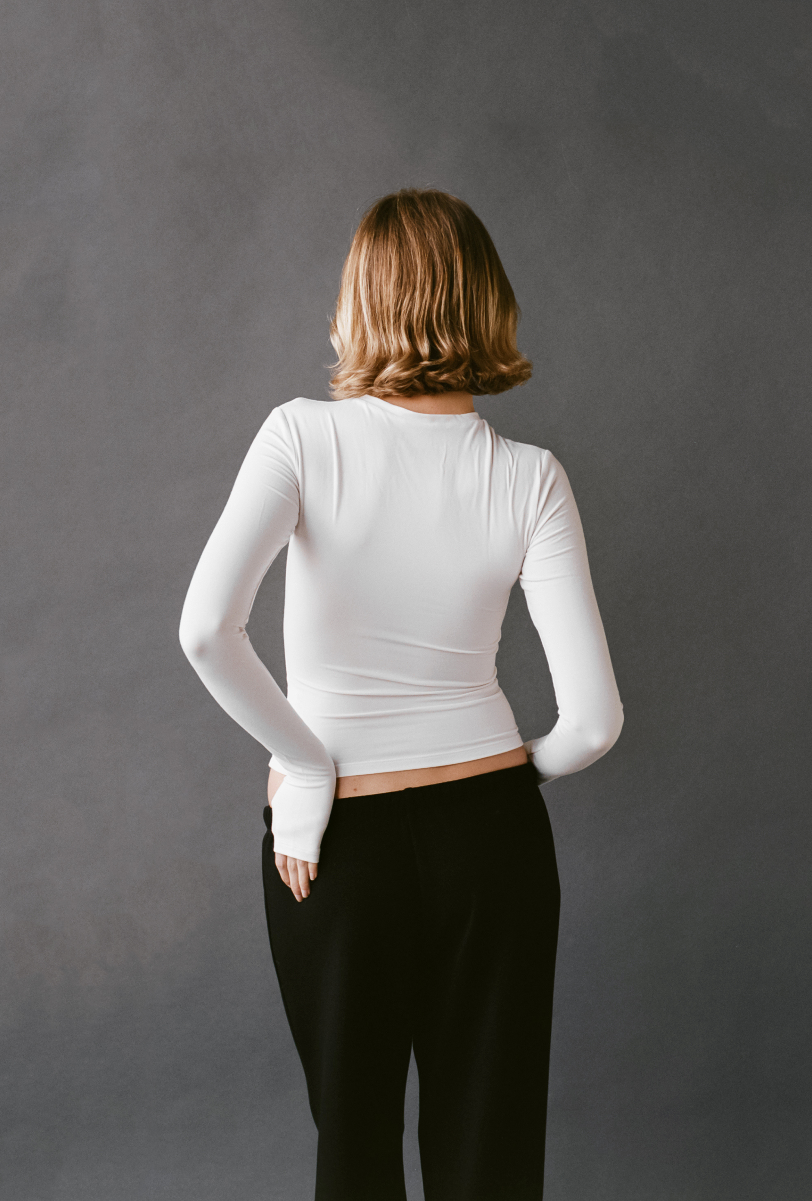 Back view of the LAUD long sleeve tee in white styled with black pants