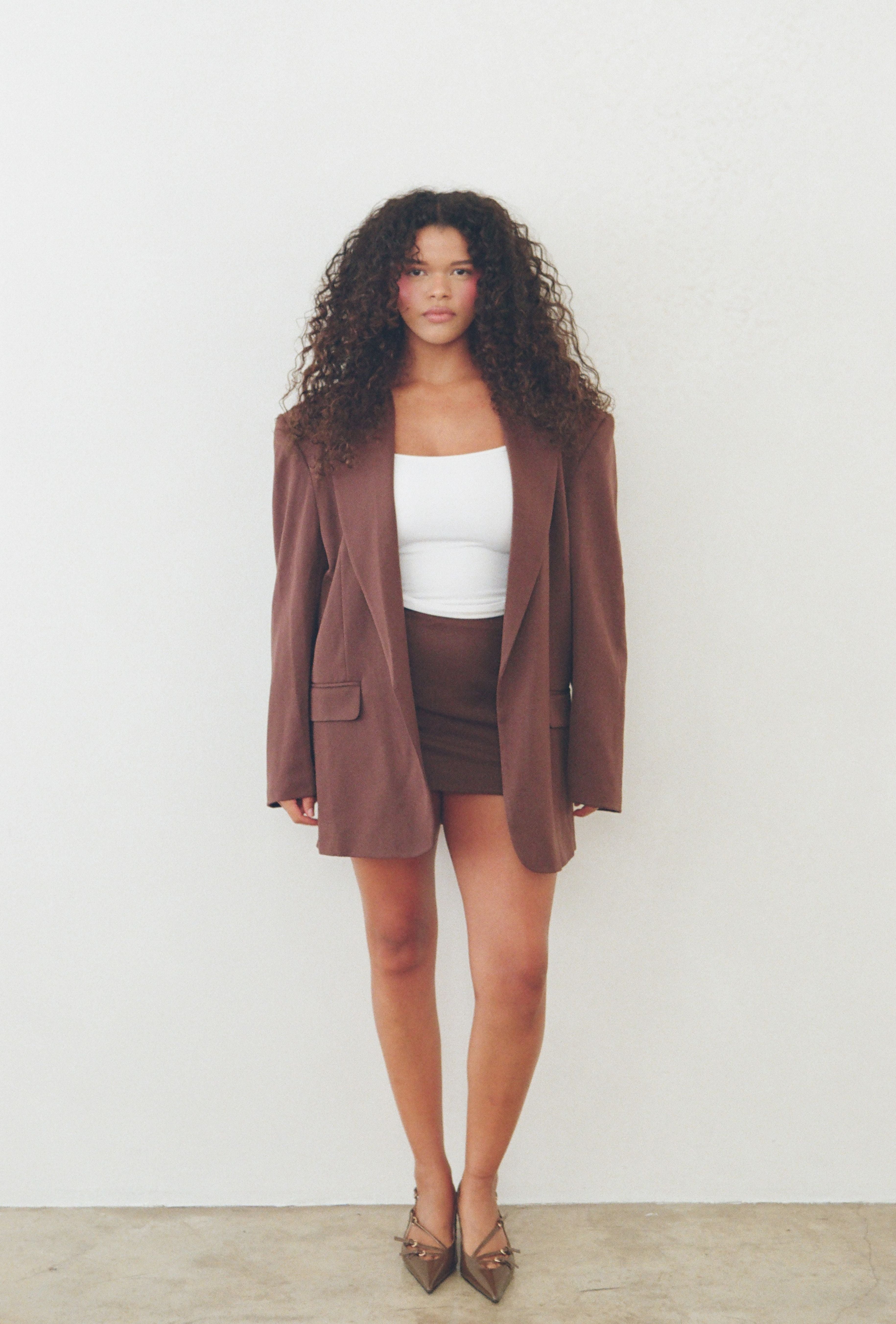 Brown tailored mini skirt styled with a white cropped tank and matching blazer