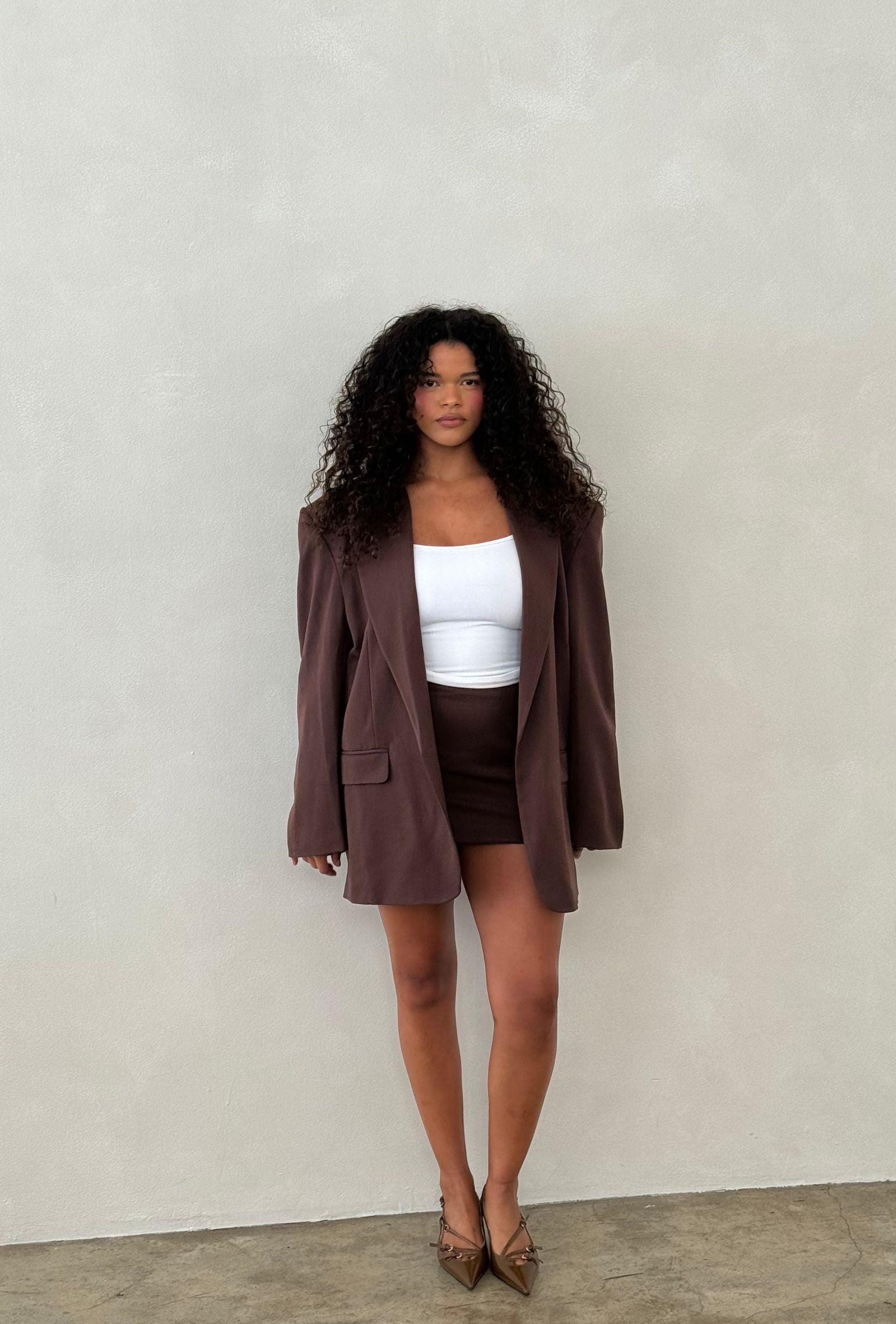 Brown oversized blazer styled with a white cropped tank and matching mini skirt